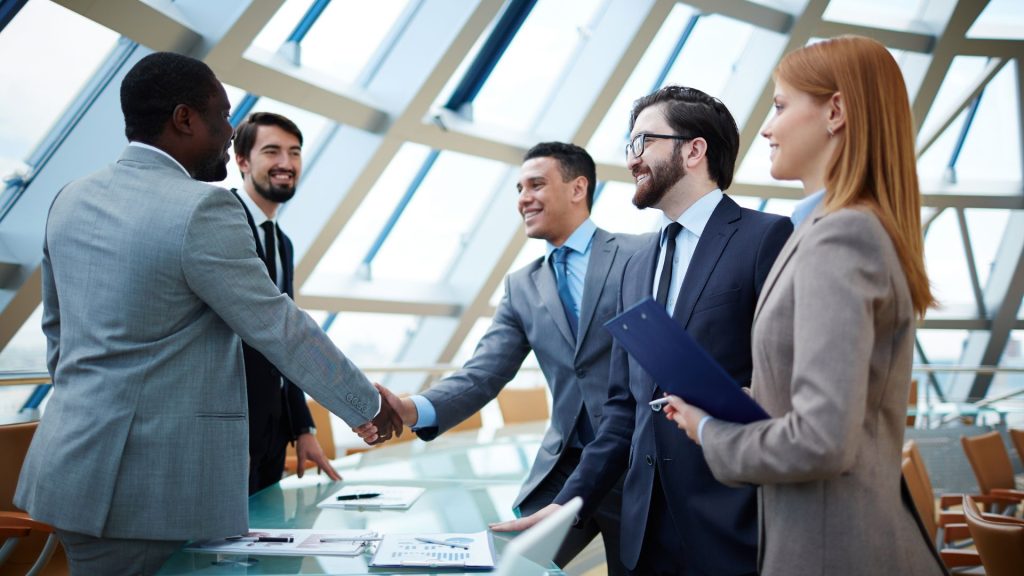 Financial professionals in an office shaking hands to close a deal with a client