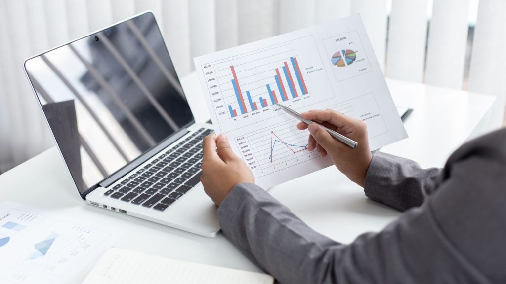 Consultor financiero revisando la información financiera en una hoja con gráficos